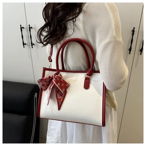 Detail of white snakeskin tote bag with red leather trim and silk heart scarf accessory