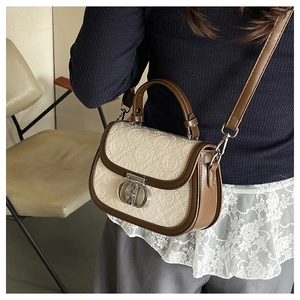 Borsa a sella in pelle marrone e beige con goffratura GSTH indossata da modella