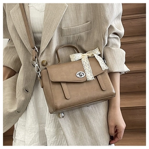 Dettaglio della borsa a tracolla vintage marrone con fiocco in pizzo bianco e chiusura