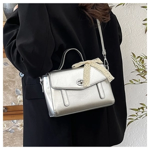 Dettaglio borsa argento metallizzato con fiocco in pizzo e trama increspata