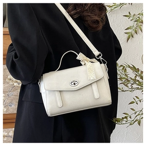 Dettaglio della piccola borsa a tracolla vintage crema con fiocco in pizzo e fibbia argento