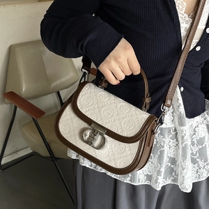 Borsa a sella bianca goffrata con finiture marroni e motivo GSTH, stile borsa a mano