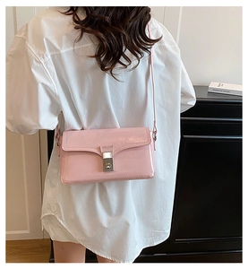 Detail view of pink patent leather crossbody bag with silver square metallic lock buckle