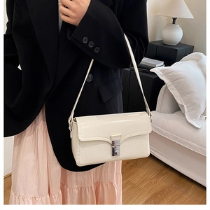 Detail of elegant cream shoulder bag with square silver metal buckle and glossy finish