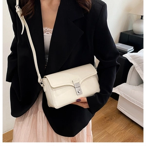 Close-up of a cream PU leather crossbody bag with silver clasp on a fashion model