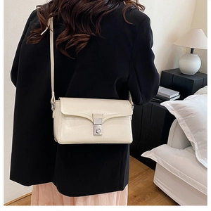 Close-up of cream leather crossbody bag featuring a sleek silver rectangular clasp
