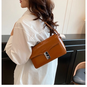 Brown leather shoulder bag with a silver rotating metal lock shown on a model