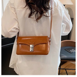 Caramel faux leather crossbody bag with silver lock clasp on a model's shoulder