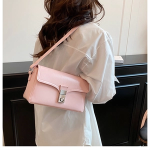 Detail of light pink crossbody bag with silver clasp lock shown on a female model