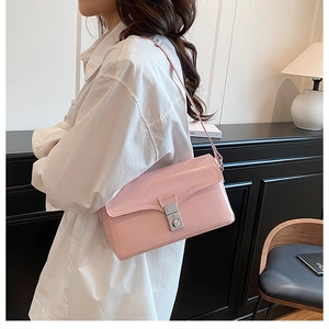 Detailed close-up of a pink leather shoulder bag with a silver square metal clasp lock