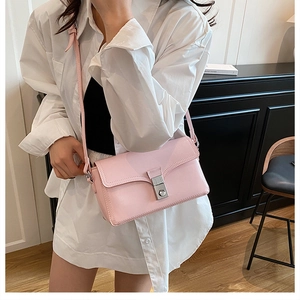Detail of light pink crossbody bag featuring a silver metal buckle and premium leather texture
