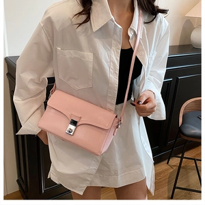 Close-up of pink leather crossbody bag with silver metal clasp on a white shirt