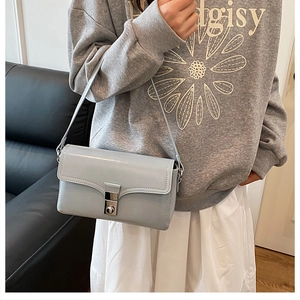 Detail of light blue shoulder bag featuring smooth leather and silver square metal lock