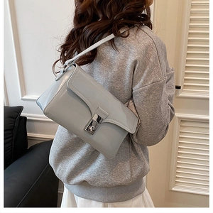 Close-up of a light grey-blue leather crossbody bag with a silver metal twist lock