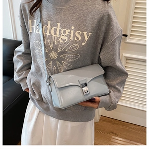 Close-up of light blue patent leather crossbody bag with silver clasp on a model