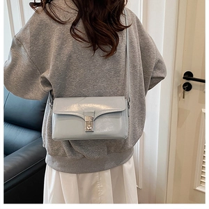 Model wearing a minimalist light blue leather crossbody bag with silver swivel lock