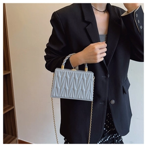 Detailed view of the V-shaped quilted texture and gold clasp on a blue box bag