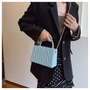 Detail of light blue box bag featuring quilted V-texture and gold chain strap