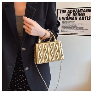 Detailed view of golden chevron evening clutch with twisted handle and metal chain strap
