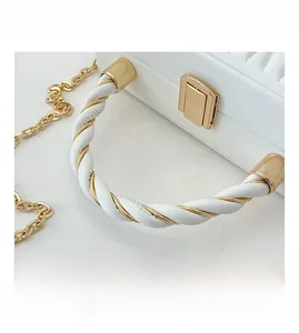 Detail of twisted white leather handle with gold metal accents and square push-lock