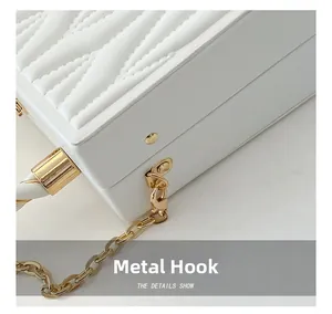 Detail shot of the golden hardware hook and quilted texture on the white chain bag