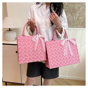 Detail der Textur der rosa Jacquard-Tragetasche mit Doppel-Xi-Zeichen und Spitzenschleife