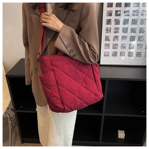 Detail of burgundy quilted tote bag showing padded nylon texture and crossbody strap