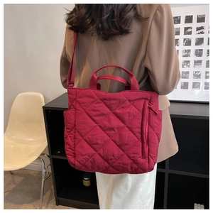 Detail view of red quilted tote bag with side zipper pocket and adjustable shoulder strap