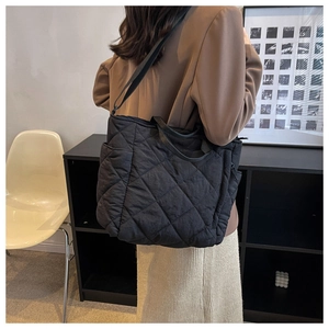 Detail of black quilted tote bag with diamond pattern stitching and adjustable strap