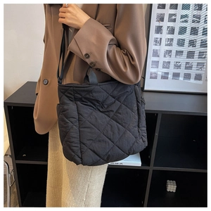 Detail of a large black quilted tote bag with diamond pattern and soft padded texture