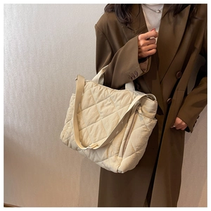 Detail of beige quilted tote bag with diamond pattern and adjustable shoulder strap