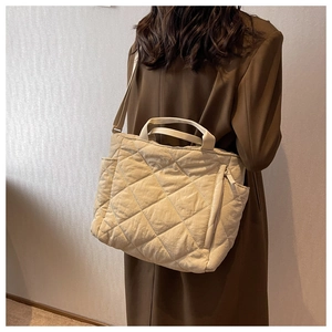 Detailed view of the diamond quilted texture on a large beige padded tote bag