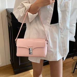 Pink patent leather square crossbody bag with silver buckle worn by a model