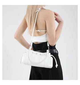 Side view of a white leather drawstring tote bag worn by a model in a modern studio