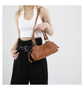 Close-up of brown drawstring tote bag with gold ring hardware and adjustable strap