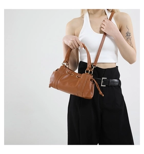 Detailed close-up of brown leather baguette bag featuring drawstring closure and gold hardware