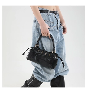 Detail of black leather tote bag with stylish gold metal eyelets and drawstring closure