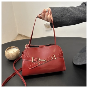 Primo piano di una borsa vintage in pelle rossa lucida con elegante fibbia d'oro