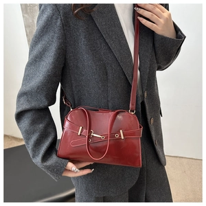 Dettaglio borsa in pelle lucida bordeaux con fibbia in metallo dorato e trama fine