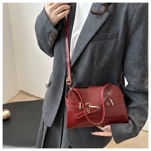 Dettaglio della borsa in pelle lucida rosso scuro con elegante fibbia in metallo dorato