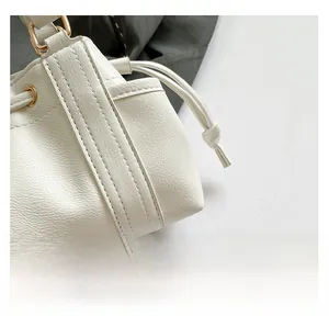 Close-up of white lychee texture leather bag featuring gold hardware and drawstring detail