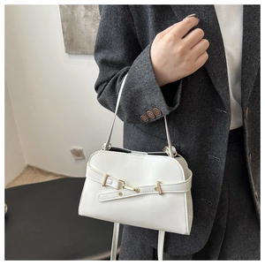 Dettaglio di una borsa bianca in pelle con fibbia dorata su un completo grigio