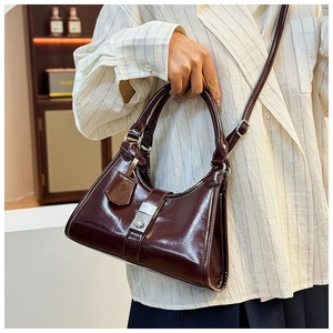 Detail of burgundy glossy leather handbag with silver clasp and adjustable shoulder strap