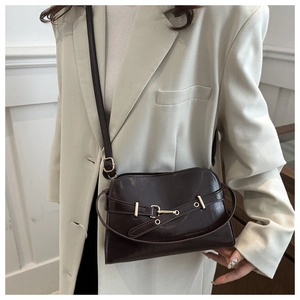 Dettaglio della borsa in pelle marrone scuro con fibbia d'oro su blazer beige