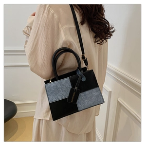 Dettaglio della borsa bicolore di tendenza con texture tweed grigio e pelle nera