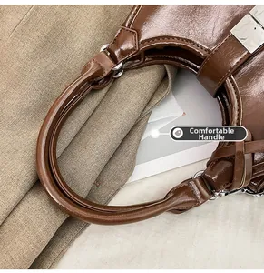 Detail of a dark brown glossy handbag with round handle and silver hardware