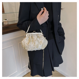 Detail of white satin shell bag featuring gold butterfly embroidery and pearl beads