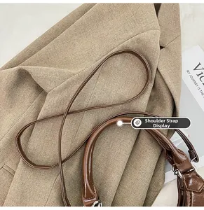 Detailed shot of dark brown dumpling bag featuring smooth top handles and leather shoulder strap