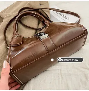 Detail view of the reinforced bottom and oil wax leather texture of a brown handbag