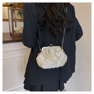 Detail of elegant pearl beaded shell bag with gold chain strap on a black blazer